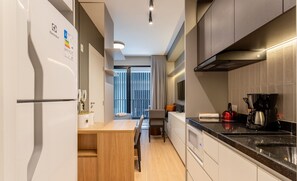 Una cocina moderna con un refrigerador empotrado, una cafetera y un hervidor sobre la encimera.