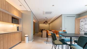 A modern kitchen with built-in appliances, a dining area with a table and chairs, and a hallway leading to another room.