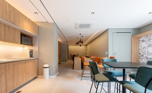 Una cocina moderna con electrodomésticos integrados, un comedor con mesa y sillas, y un pasillo que conduce a otra habitación.