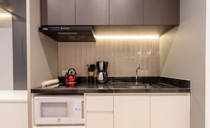 A modern kitchen with a microwave, coffee maker, and kettle on the countertop. - Modern in Ecos Vila Madalena Cond. Evm1012 (São Paulo)