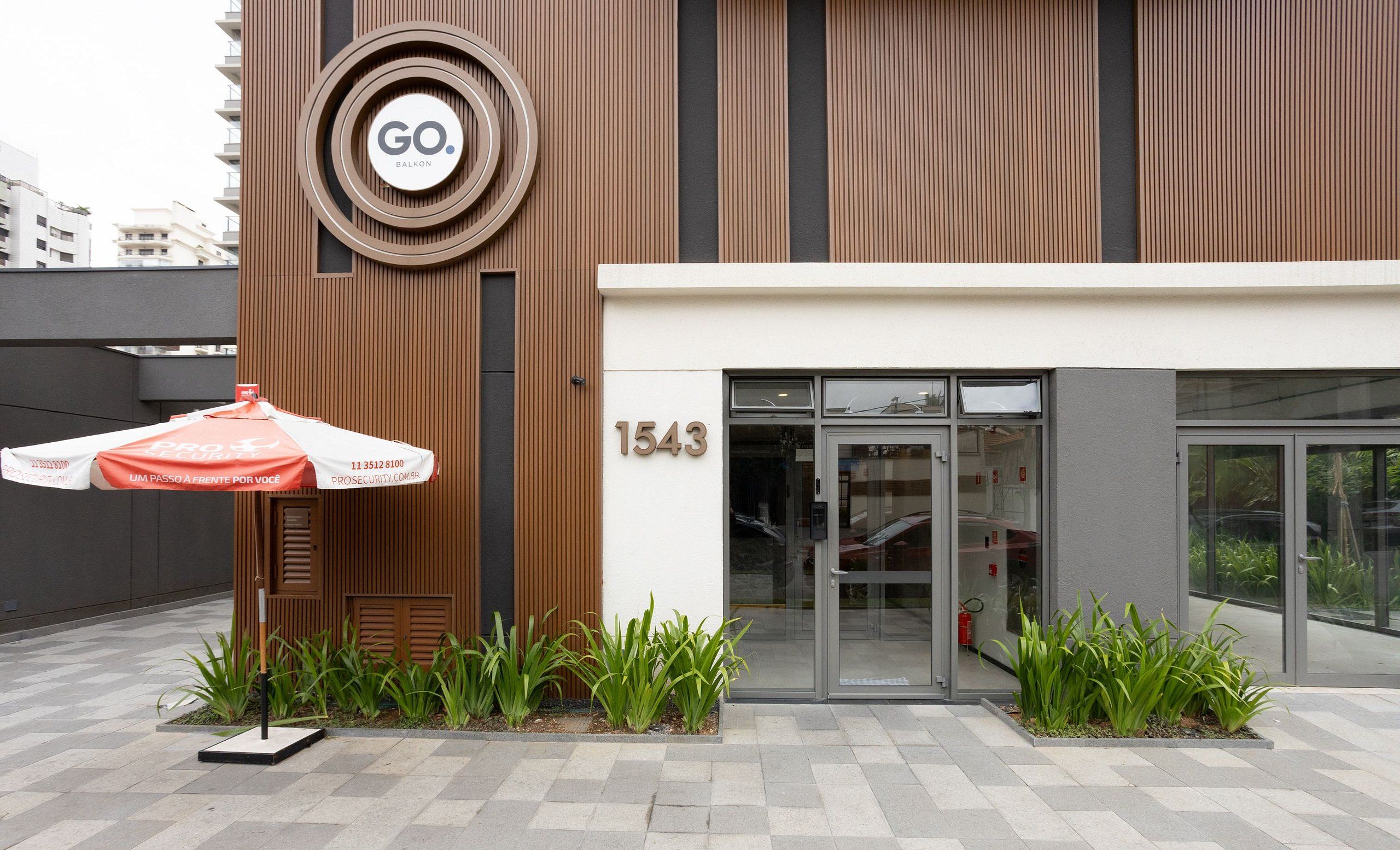 Un edificio moderno con un logotipo circular, una sombrilla de seguridad y el número 1543 en la fachada.