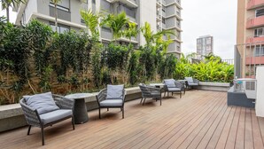 An outdoor patio with wicker furniture and a stone wall. - Estúdio em SP perto do metrô | GBA908 (São Paulo)