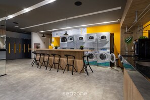 Un moderno lavadero con varias lavadoras, taburetes altos y una encimera de madera.