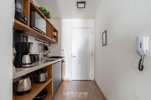 Une cuisine équipée d’une machine à café, d’une bouilloire et d’étagères remplies d’ustensiles de cuisine.