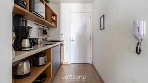Una cocina con cafetera, hervidor y estantes con utensilios de cocina.