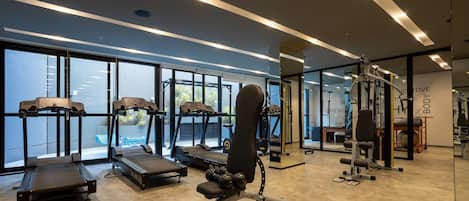 Un gimnasio moderno con cintas de correr, máquinas de pesas y pesas libres.