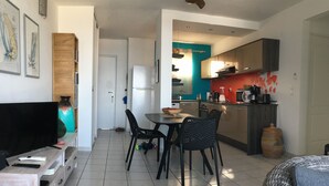 A modern living room with a TV, a coffee table, and a dining area with chairs. - Superb Caiali Blue apartment (Les Trois-Îlets)
