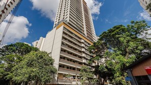A tall, modern building with multiple floors, surrounded by trees and other buildings. - Beautiful Studio With Pool in Campo Belo Hmc0320 (São Paulo)