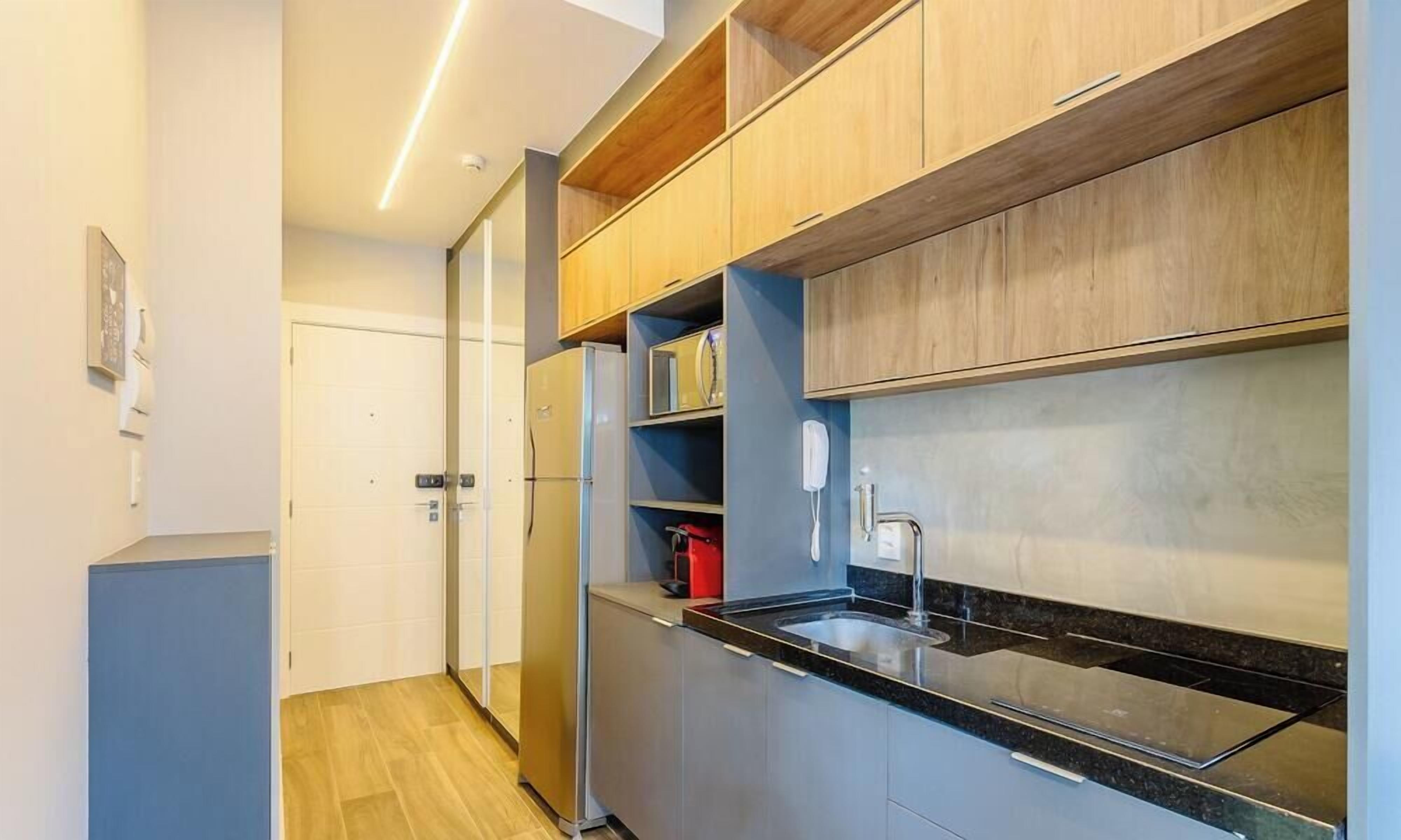 A modern kitchen with built-in appliances, a black countertop, and wooden cabinetry.