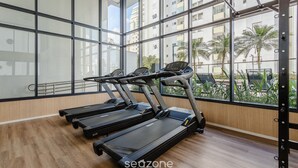 A gym with treadmills, large windows, and a view of palm trees and buildings. - Beautiful Studio With Pool in Campo Belo Hmc0320 (São Paulo)