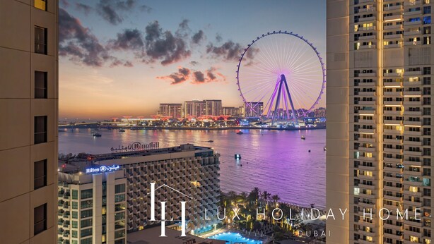 A hotel with a view of a Ferris wheel and a body of water at dusk. - LUX  The Luxury Sunny JBR Beach Views 2  (Dubai)
