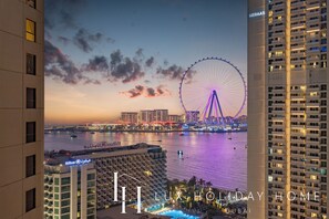 A hotel with a view of a Ferris wheel and a body of water at dusk. - LUX The Luxury Sunny JBR Beach Views 2 (Dubai)