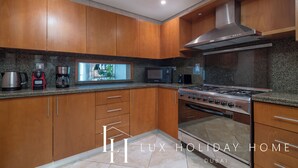 A modern kitchen with wooden cabinets, a stainless steel stove, and a microwave. - LUX  The Luxury Sunny JBR Beach Views 2  (Dubai)