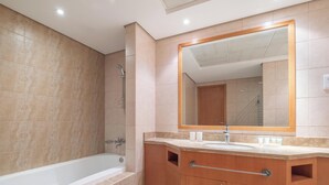 Ein modernes Badezimmer mit einer Badewanne, einem großen Spiegel und Holzschränken.