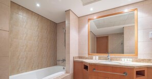 A modern bathroom with a bathtub, a large mirror, and wooden cabinetry. - LUX  The Luxury Sunny JBR Beach Views 2  (Dubai)