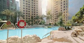A swimming pool area with a no diving sign, surrounded by high-rise buildings and palm trees. - LUX  The Luxury Sunny JBR Beach Views 2  (Dubai)