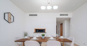 A modern dining room with a wooden table set for six, light-colored chairs, and a small potted plant. - LUX The Luxury Sunny JBR Beach Views 2 (Dubai)