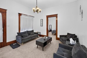 Un salon avec un canapé de couleur sombre, une table basse et un miroir.