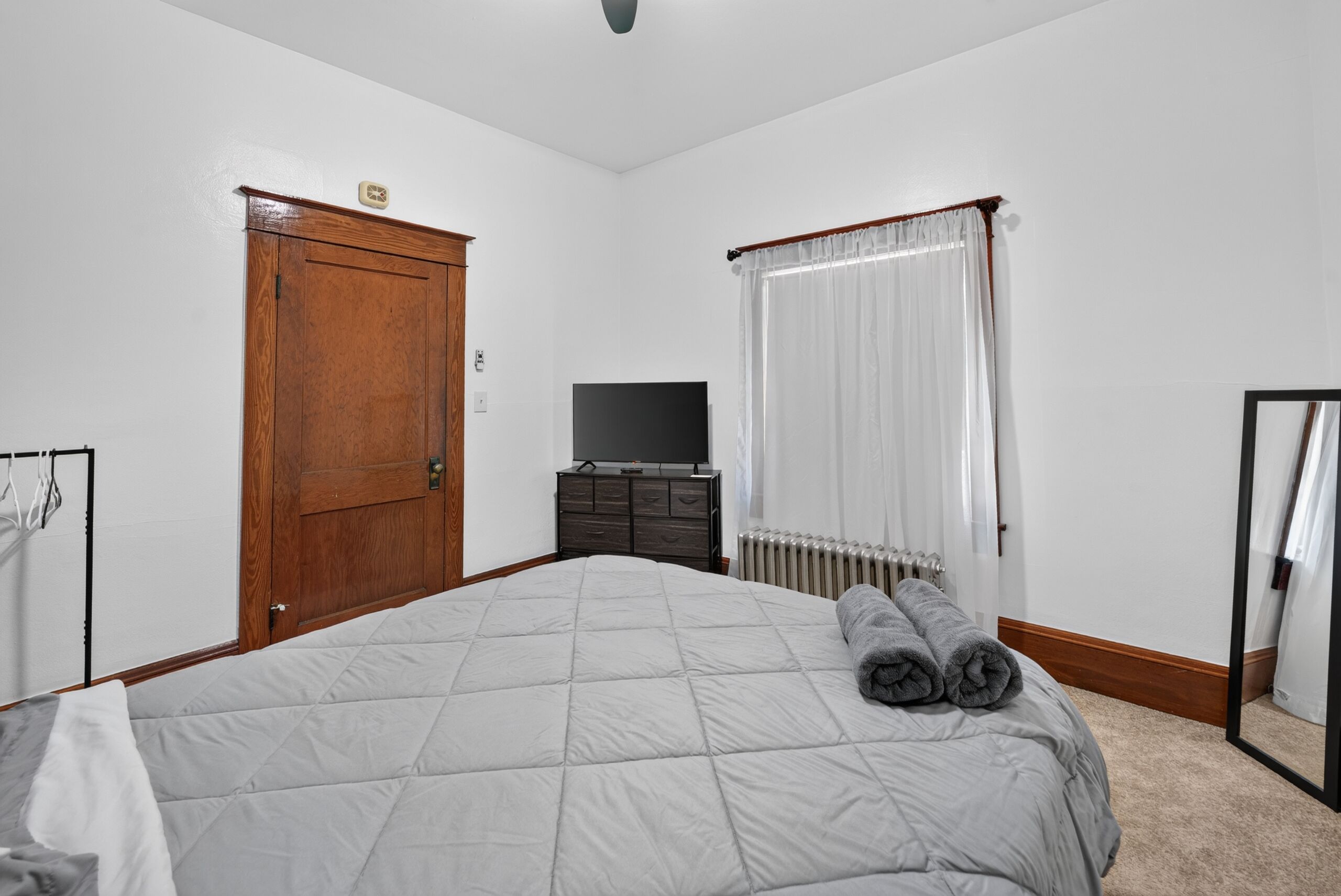 A bedroom with a bed, a television, a radiator, and a wardrobe.
