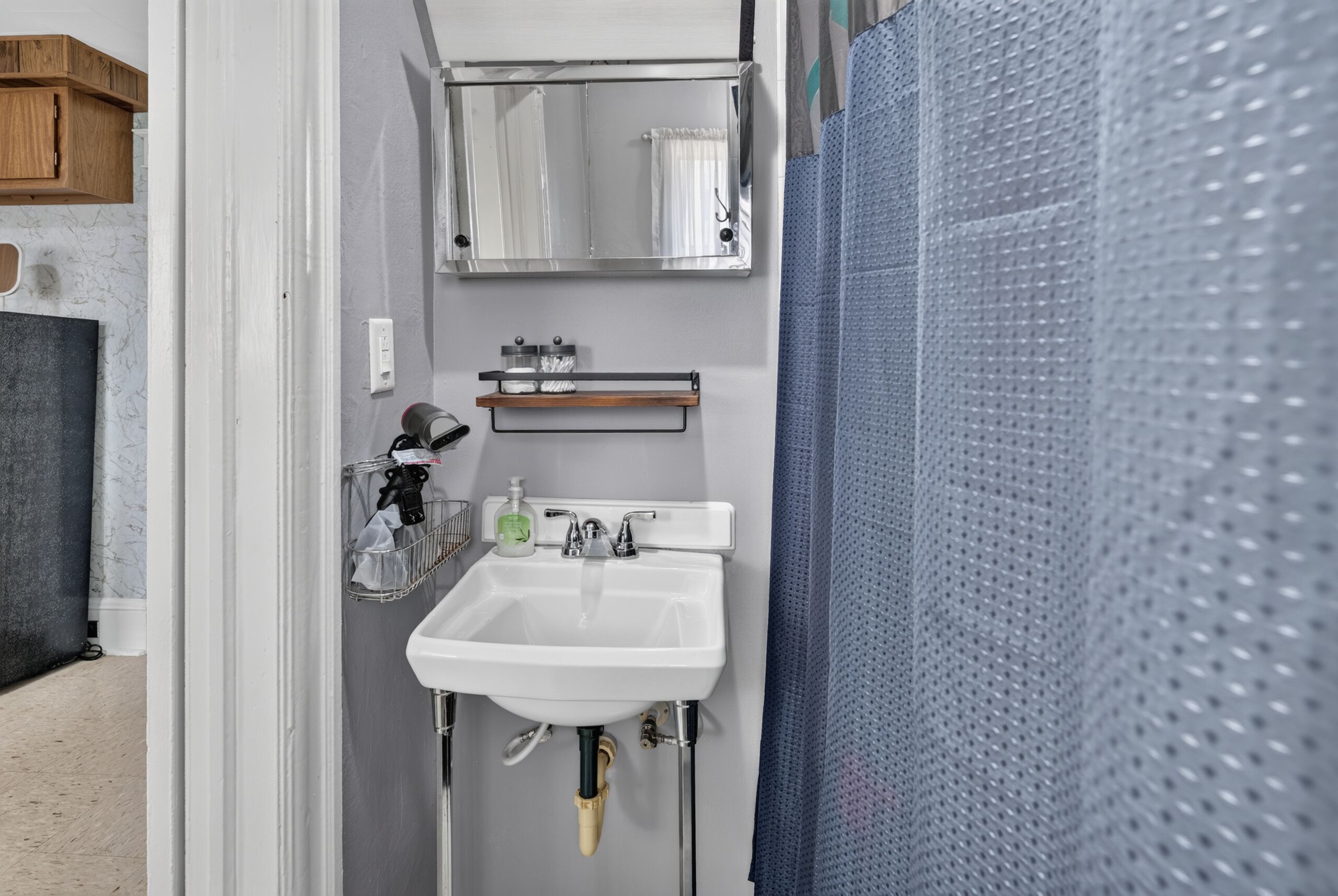 A bathroom with a white sink, a mirror, and a towel rack.