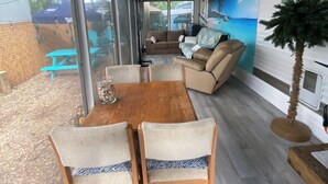 Een moderne woonkamer met een houten eettafel, twee stoelen, een bank en een groot raam.
