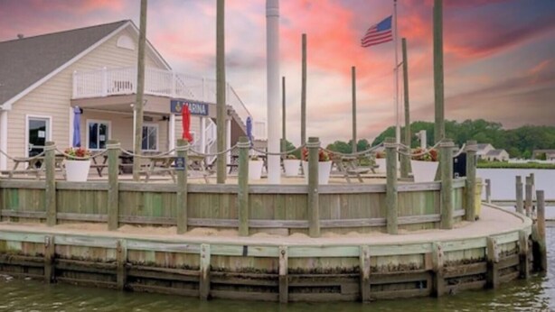 Een gebouw aan het water met een steiger, met daarin een restaurant genaamd "MARINA" en een Amerikaanse vlag.