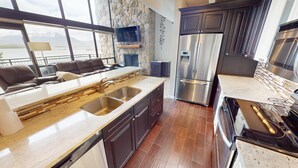 A modern kitchen with a stone backsplash, stainless steel appliances, and a view of the sea through large windows. - On Lake, WOW Views, Big Deck! Walk to Amp, Events, Parks, Marina, Tiki Bar (Dillon)