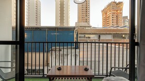 A balcony with a table and chairs, a view of tall buildings, and a construction site in the background.