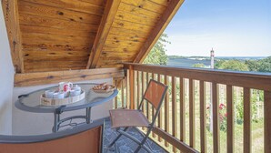 Een houten balkon met een tafel en stoelen, met uitzicht op een prachtig landschap.