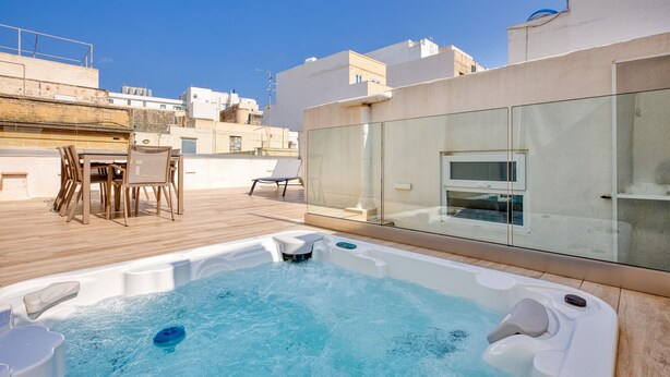 A rooftop terrace with a hot tub, a table with chairs, and a glass-enclosed room. - Impressive 3 bedrooms, sun terrace, jacuzzi AMRA1-1 (Sliema)