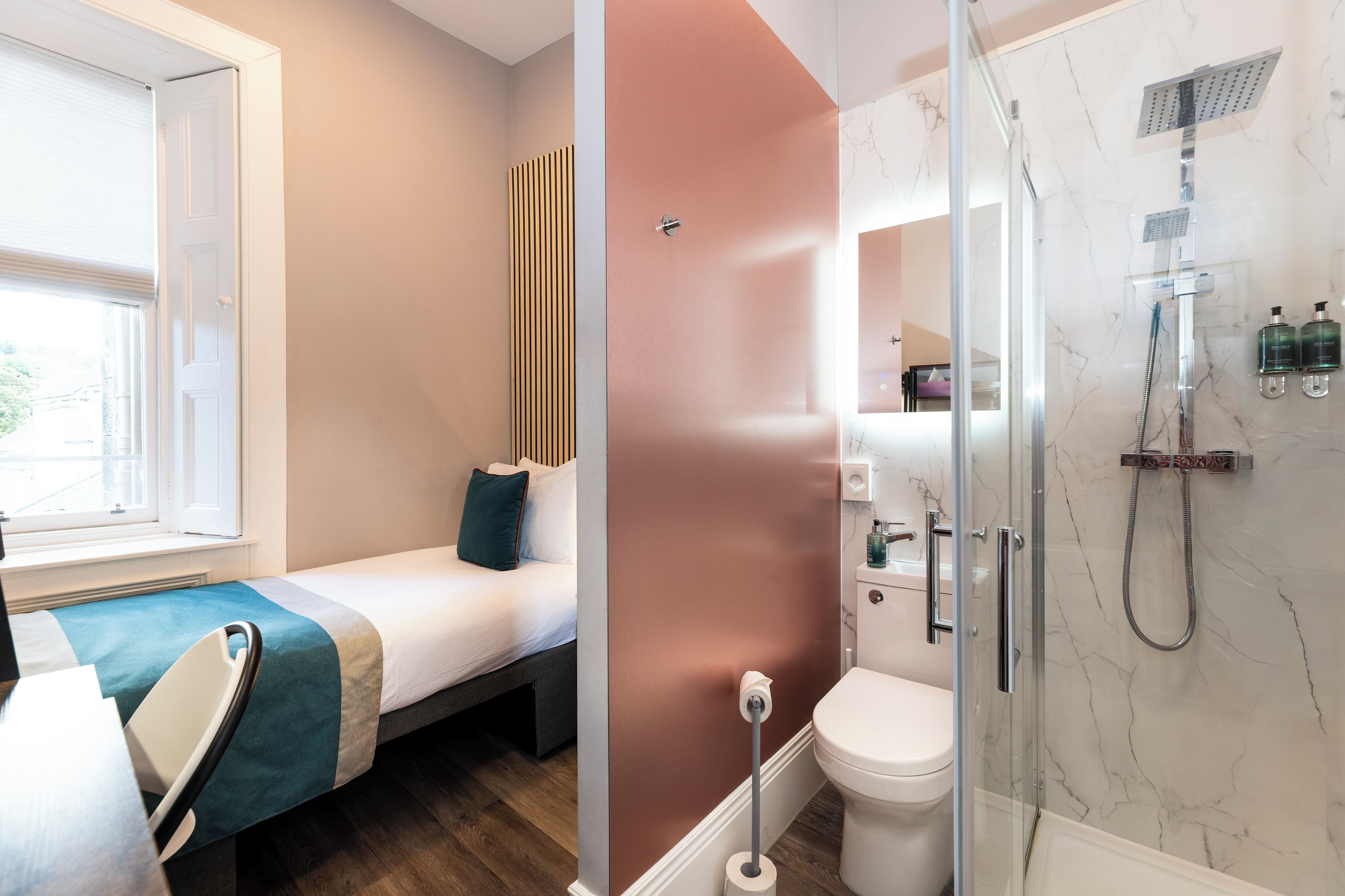 Un baño moderno con ducha, inodoro y cama con vistas al exterior.