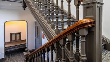 A grand staircase with ornate balusters and a wooden handrail, leading to an upper floor.