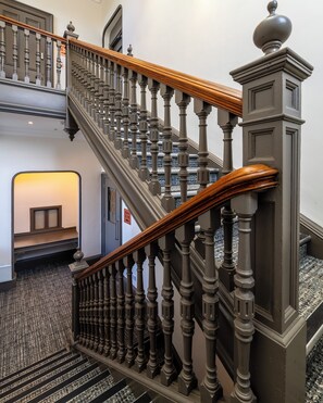 A grand staircase with ornate balusters and a wooden handrail, leading to an upper floor. - Linen Bank (Linlithgow)