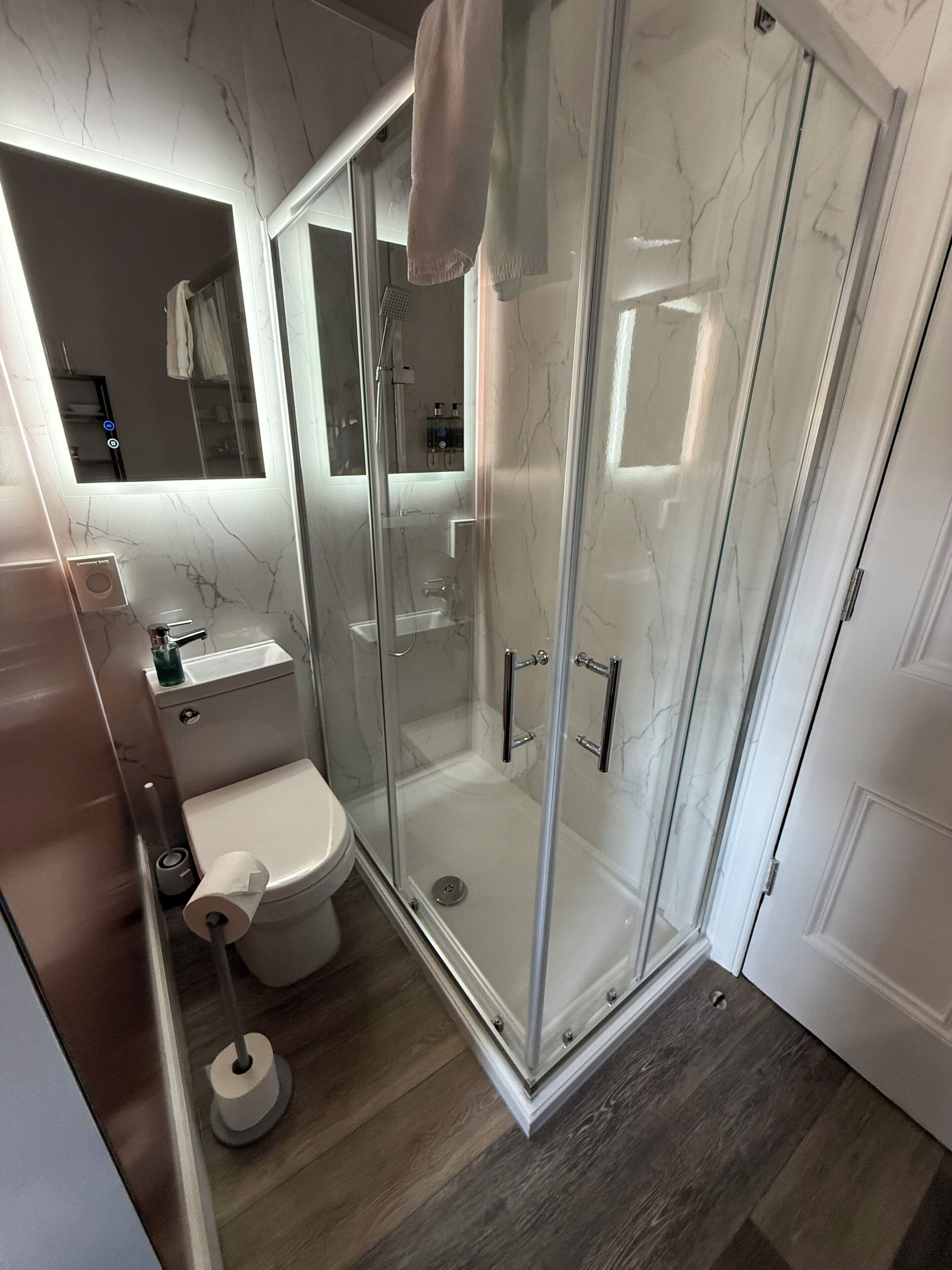 A modern bathroom with a glass-enclosed shower, a toilet, and a sink.