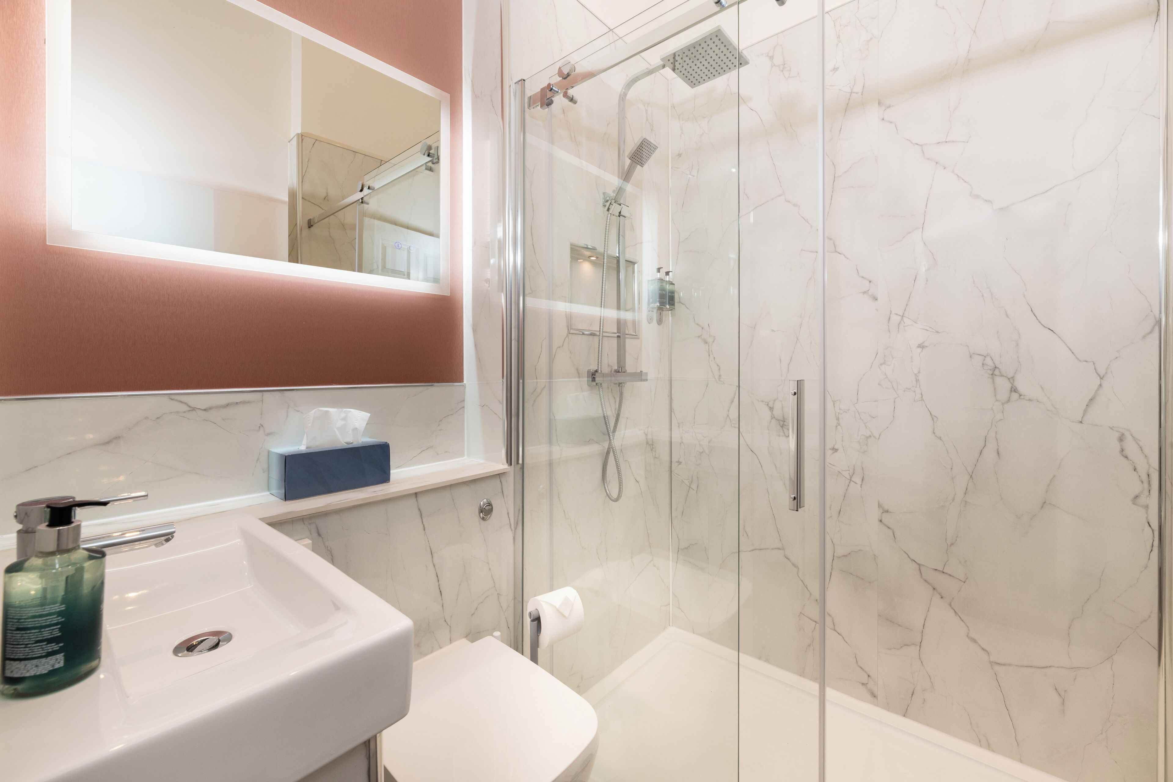 A bathroom with a glass-enclosed shower, a white sink, and a mirror above the sink.