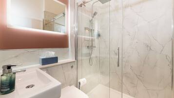 A bathroom with a glass-enclosed shower, a white sink, and a mirror above the sink.