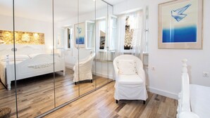 A modern bedroom with a large mirror, a white bed, and a chair. - Korifo Old Town by Corfu Escapes (Corfu)