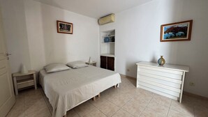 A bedroom with a bed, bedside tables, a dresser, and two framed pictures on the walls.