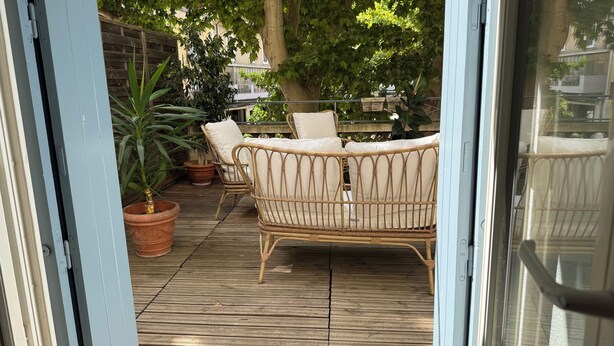 A wooden deck with wicker furniture and potted plants.