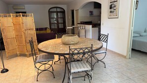 A round dining table with a woven centerpiece, surrounded by four chairs with cushioned seats and backs.