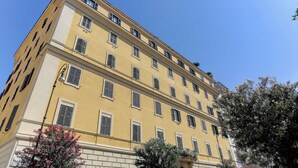 A multi-story yellow building with evenly spaced windows and a symmetrical facade.