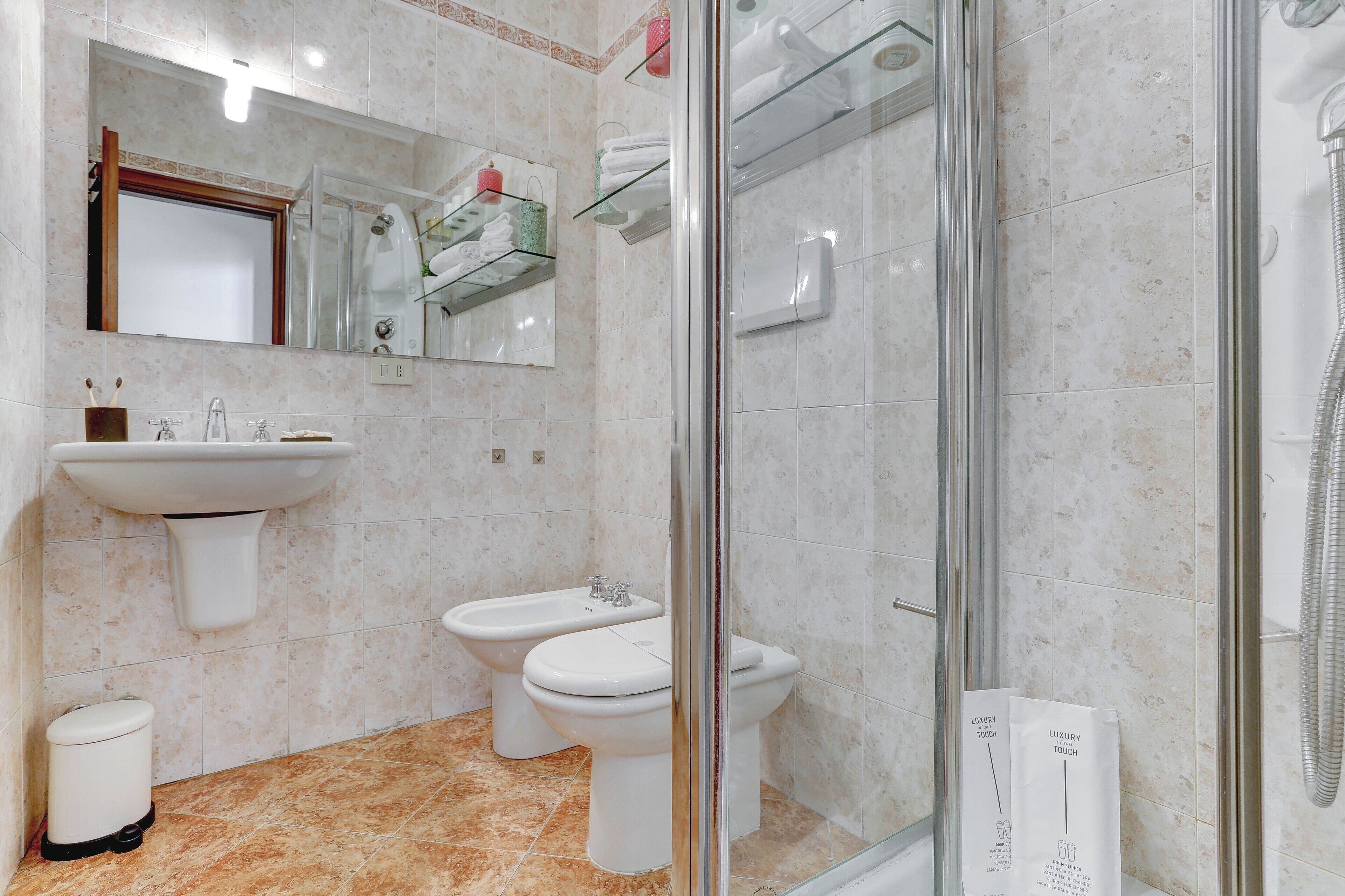 A modern bathroom with a glass-enclosed shower, a sink, and a toilet.
