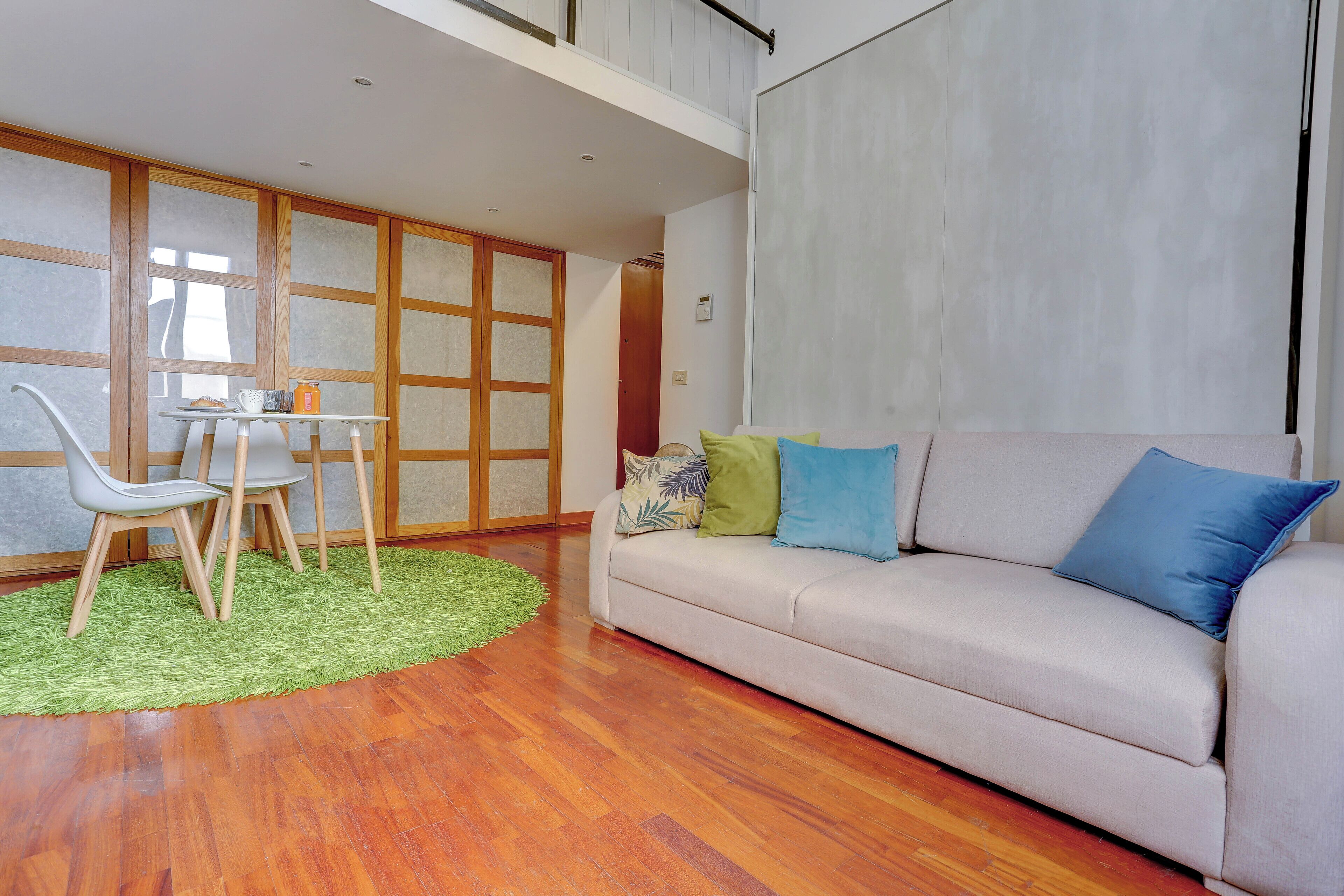 A modern living room with a sofa, chairs, a small table, and a green rug.