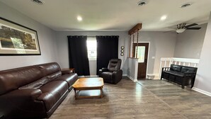 Un salon avec un canapé en cuir marron, une table basse en bois, un fauteuil inclinable et un canapé noir.