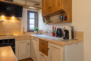 A kitchen with wooden cabinets, a built-in oven, a coffee maker, and a window with a view.