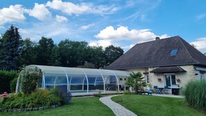 Une maison avec une serre, un chemin de pierres et une pelouse.