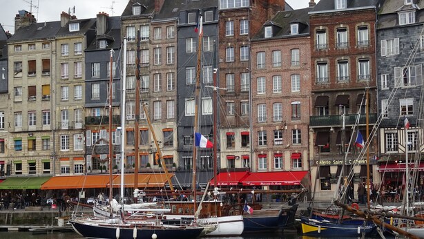 Un port où de nombreux bateaux sont amarrés, entouré de bâtiments historiques présentant différents styles architecturaux.