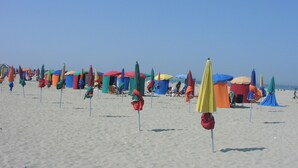 Une plage parsemée de nombreux parasols colorés et de cabanes de plage.