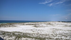 A beach with white sand and sparse vegetation under a clear blue sky. - 255 El Matador 1 Bedroom Condo (Fort Walton Beach)