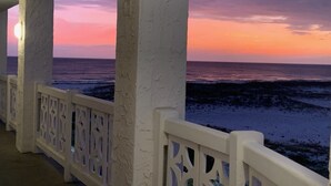 A coastal view from a balcony with white railings and columns, overlooking the sea during sunset. - 255 El Matador 1 Bedroom Condo (Fort Walton Beach)
